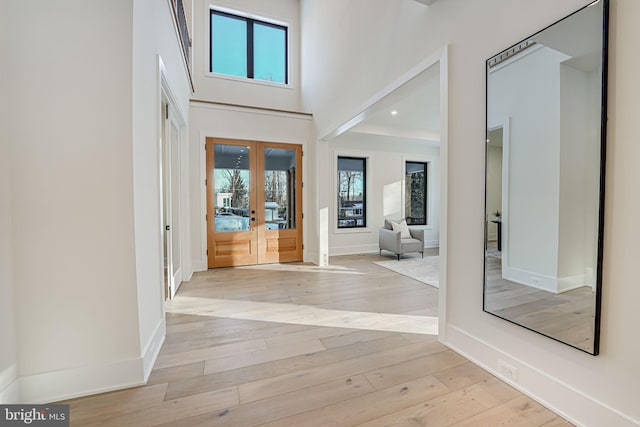 entrance foyer featuring french doors, a high ceiling, and light hardwood / wood-style flooring