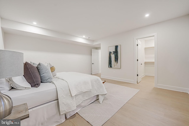 bedroom featuring a walk in closet, a closet, and light hardwood / wood-style floors