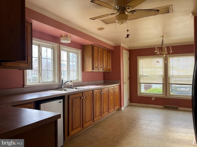 kitchen featuring stainless steel dishwasher, ornamental molding, ceiling fan with notable chandelier, sink, and decorative light fixtures