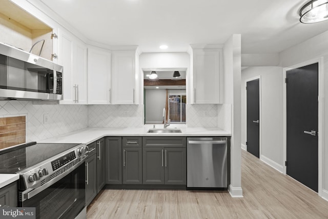 kitchen featuring gray cabinetry, white cabinets, sink, light hardwood / wood-style floors, and stainless steel appliances