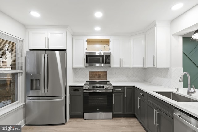 kitchen with light stone countertops, stainless steel appliances, white cabinetry, and sink