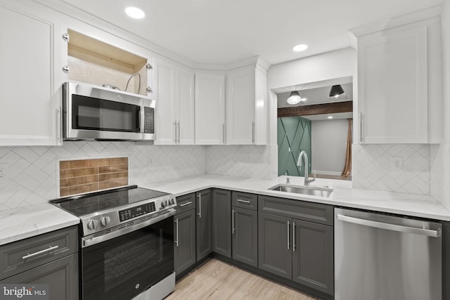 kitchen with white cabinetry, sink, stainless steel appliances, and light stone counters