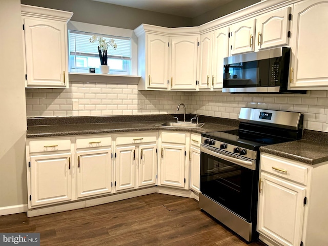 kitchen featuring stainless steel appliances, dark wood-type flooring, sink, an inviting chandelier, and white cabinetry