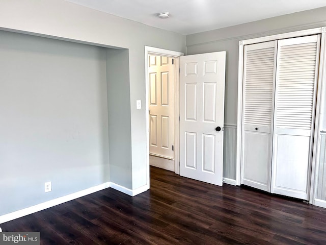 unfurnished bedroom featuring a closet and dark wood-type flooring