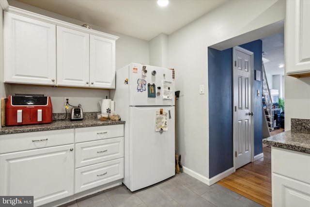 kitchen featuring white cabinets, white refrigerator, and light tile patterned floors