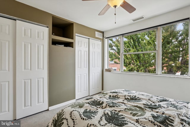 bedroom featuring light carpet, two closets, and ceiling fan