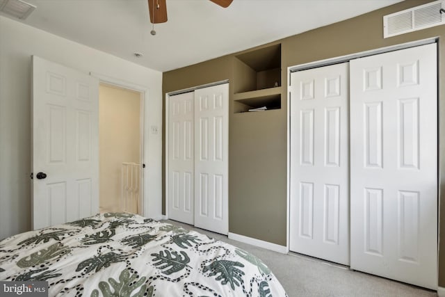 carpeted bedroom with two closets and ceiling fan