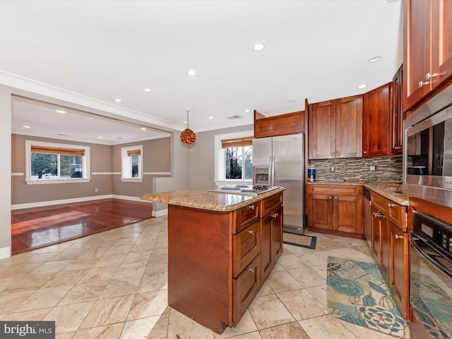 kitchen featuring appliances with stainless steel finishes, backsplash, crown molding, pendant lighting, and a center island