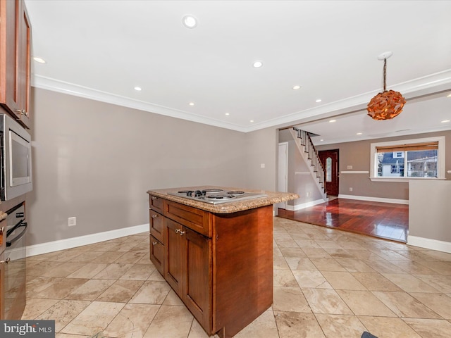 kitchen featuring stainless steel microwave, white stovetop, crown molding, light stone countertops, and a kitchen island