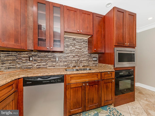 kitchen with backsplash, light stone counters, sink, and appliances with stainless steel finishes