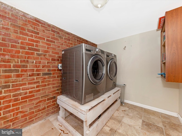 laundry area featuring washer and dryer and brick wall