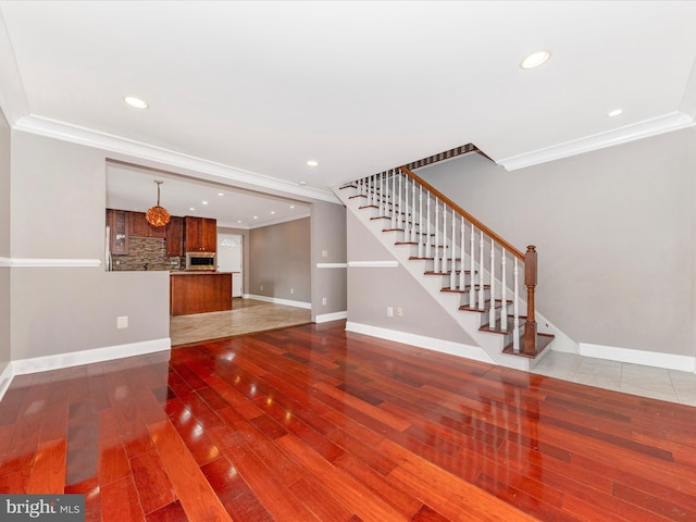 unfurnished living room with hardwood / wood-style flooring and crown molding