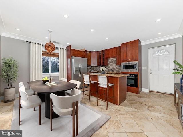 kitchen featuring stainless steel appliances, a kitchen island, tasteful backsplash, and ornamental molding