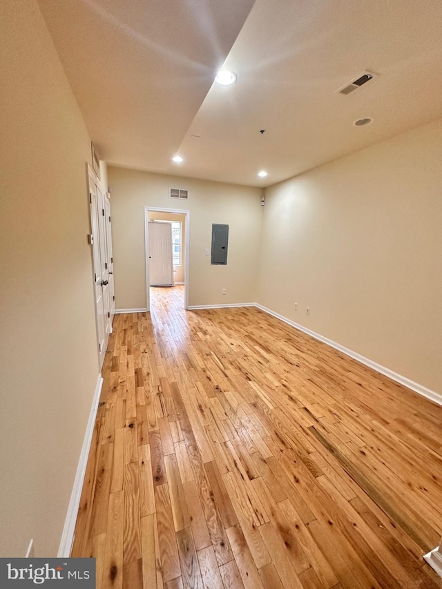 spare room with electric panel and light hardwood / wood-style flooring