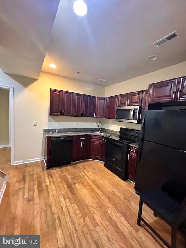 kitchen with black appliances, sink, and light hardwood / wood-style flooring