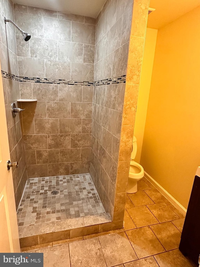 bathroom featuring tiled shower and toilet