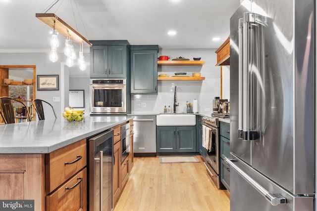 kitchen with pendant lighting, backsplash, sink, wine cooler, and appliances with stainless steel finishes