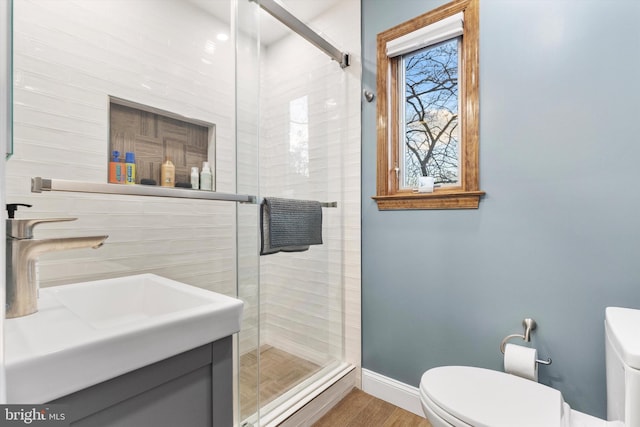 bathroom with hardwood / wood-style floors, vanity, toilet, and a shower with shower door