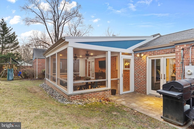 rear view of property featuring a playground, a sunroom, and a lawn