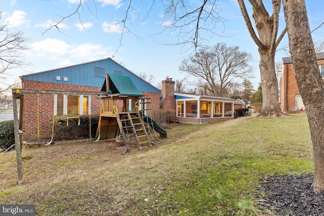 rear view of house with a playground and a yard