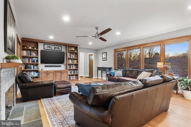 living room with ceiling fan, ornamental molding, and a fireplace