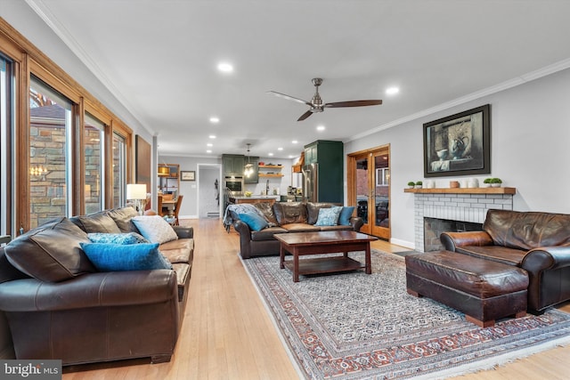 living room featuring light hardwood / wood-style floors, a brick fireplace, ceiling fan, and crown molding