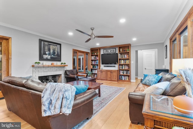 living room with a fireplace, light wood-type flooring, ceiling fan, and crown molding