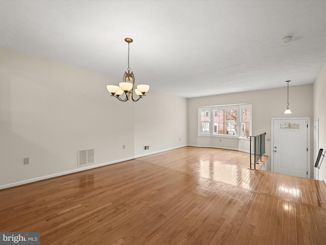 unfurnished living room featuring wood-type flooring and an inviting chandelier