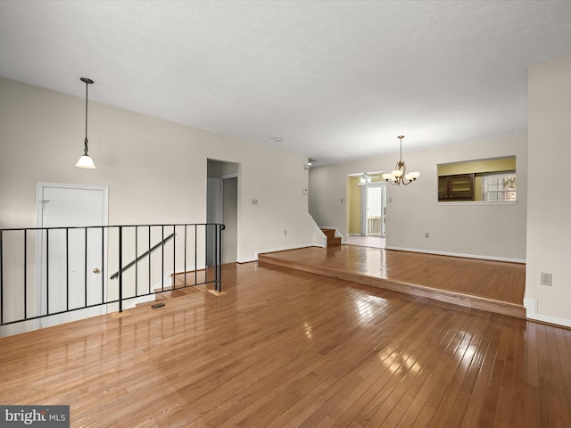 unfurnished room with hardwood / wood-style floors and an inviting chandelier