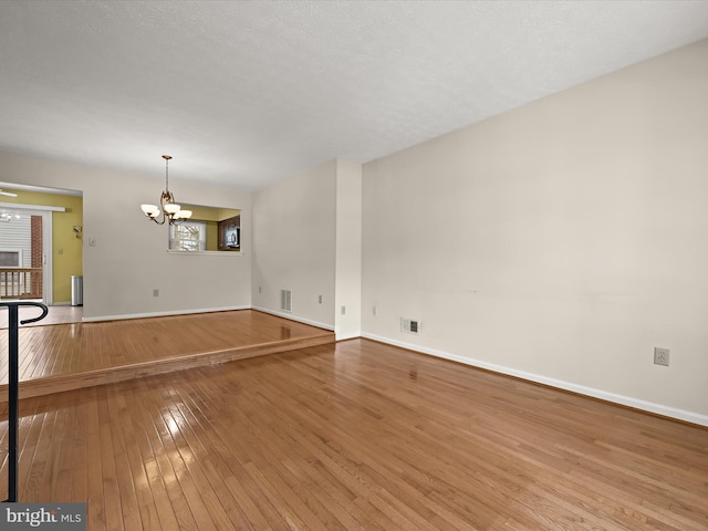 empty room featuring a notable chandelier and hardwood / wood-style floors