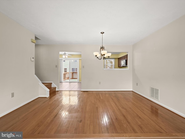 unfurnished room with hardwood / wood-style flooring and ceiling fan with notable chandelier