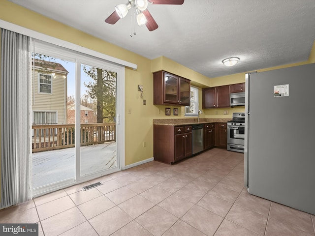 kitchen featuring appliances with stainless steel finishes, a textured ceiling, sink, dark brown cabinetry, and light tile patterned flooring