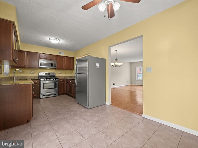 kitchen with sink, pendant lighting, stainless steel appliances, light stone counters, and light tile patterned flooring