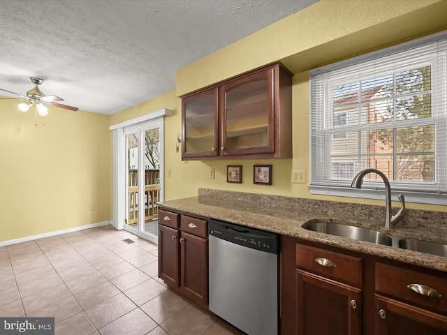 kitchen featuring a textured ceiling, light tile patterned floors, stainless steel dishwasher, sink, and plenty of natural light