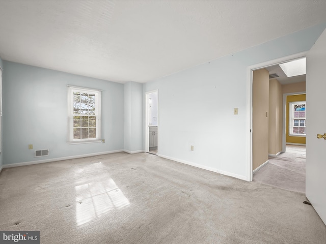 carpeted empty room with a skylight