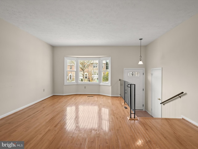 unfurnished living room with light hardwood / wood-style flooring and a textured ceiling