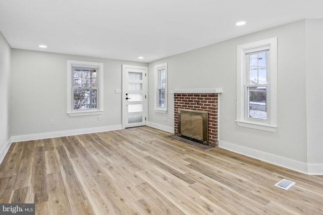 unfurnished living room featuring a fireplace and light hardwood / wood-style flooring