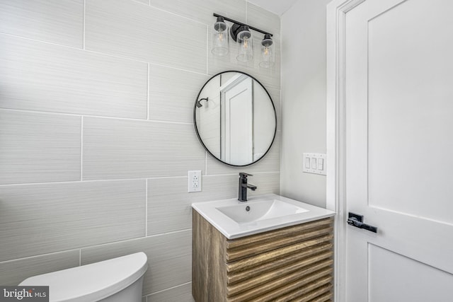 bathroom featuring vanity, tile walls, and toilet