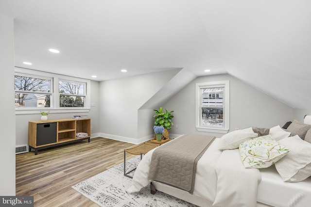 bedroom featuring multiple windows, wood-type flooring, and lofted ceiling