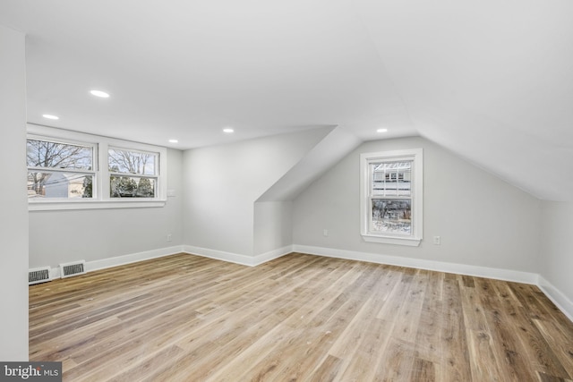 additional living space with lofted ceiling, a healthy amount of sunlight, and light wood-type flooring