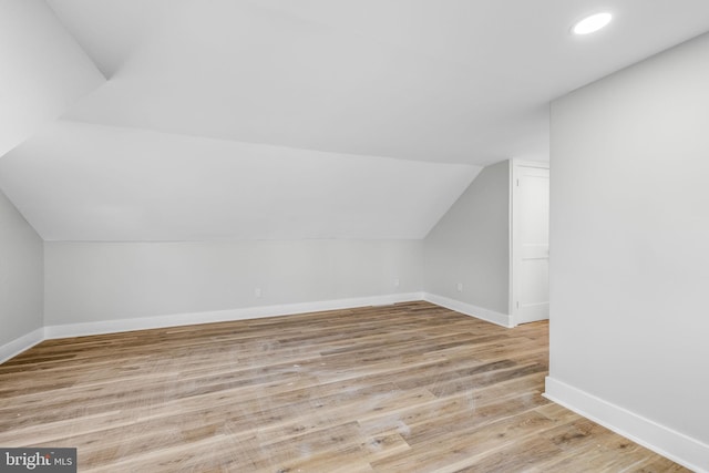 additional living space featuring light wood-type flooring and lofted ceiling