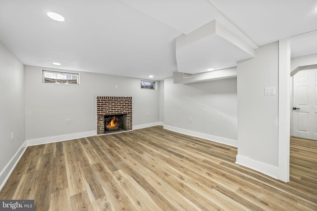 basement featuring a fireplace and light hardwood / wood-style flooring