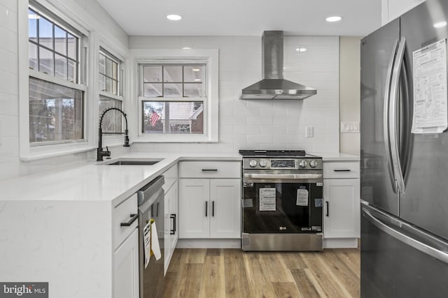 kitchen with white cabinets, sink, wall chimney exhaust hood, and appliances with stainless steel finishes