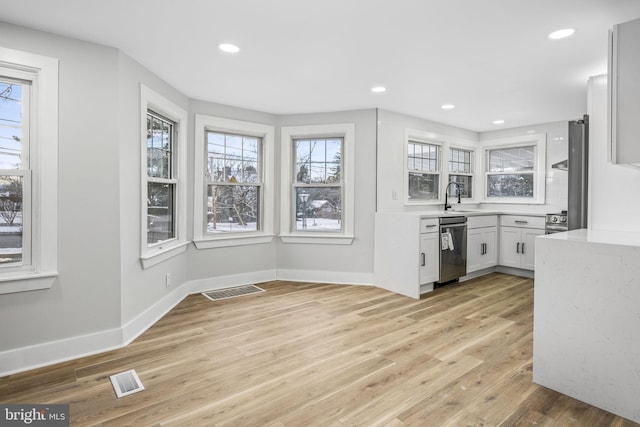 kitchen featuring white cabinets, light hardwood / wood-style floors, stainless steel dishwasher, and sink