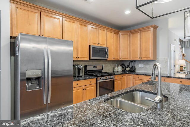 kitchen featuring dark stone countertops, decorative backsplash, sink, and appliances with stainless steel finishes