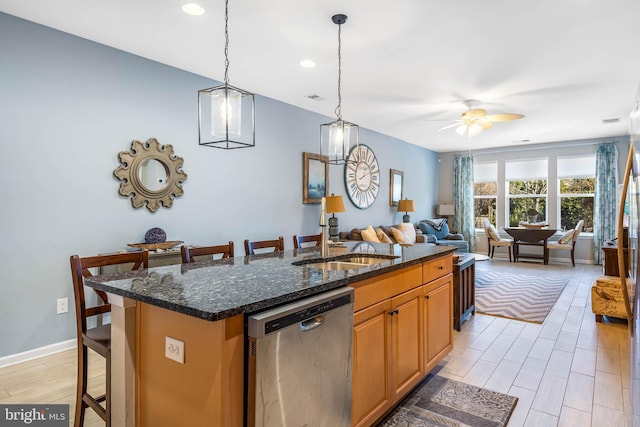 kitchen featuring a kitchen bar, dark stone countertops, an island with sink, and stainless steel dishwasher