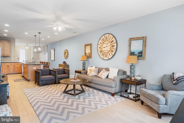 living room with light wood-type flooring, ceiling fan, and sink