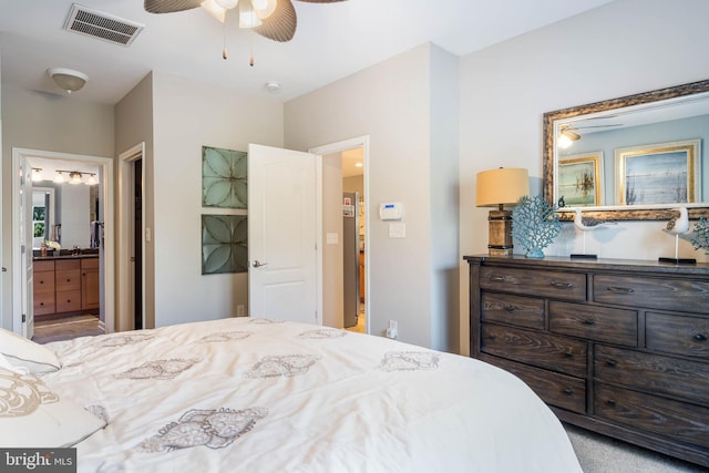 carpeted bedroom with ensuite bathroom and ceiling fan