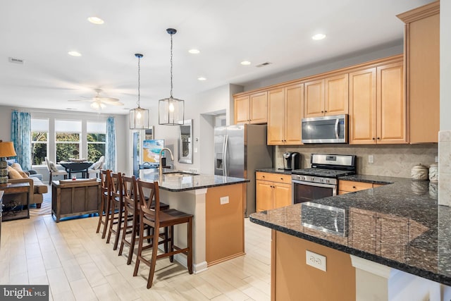 kitchen with pendant lighting, a center island with sink, sink, ceiling fan, and stainless steel appliances