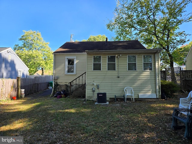 rear view of house featuring central AC and a lawn